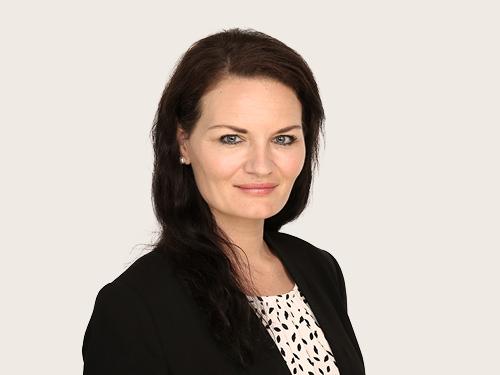Patricia Baron, aus dem Claims Underwriting bei Hiscox. Eine Person mit langen Haaren trägt einen schwarzen Blazer über einem hell-gepunkteten Oberteil.