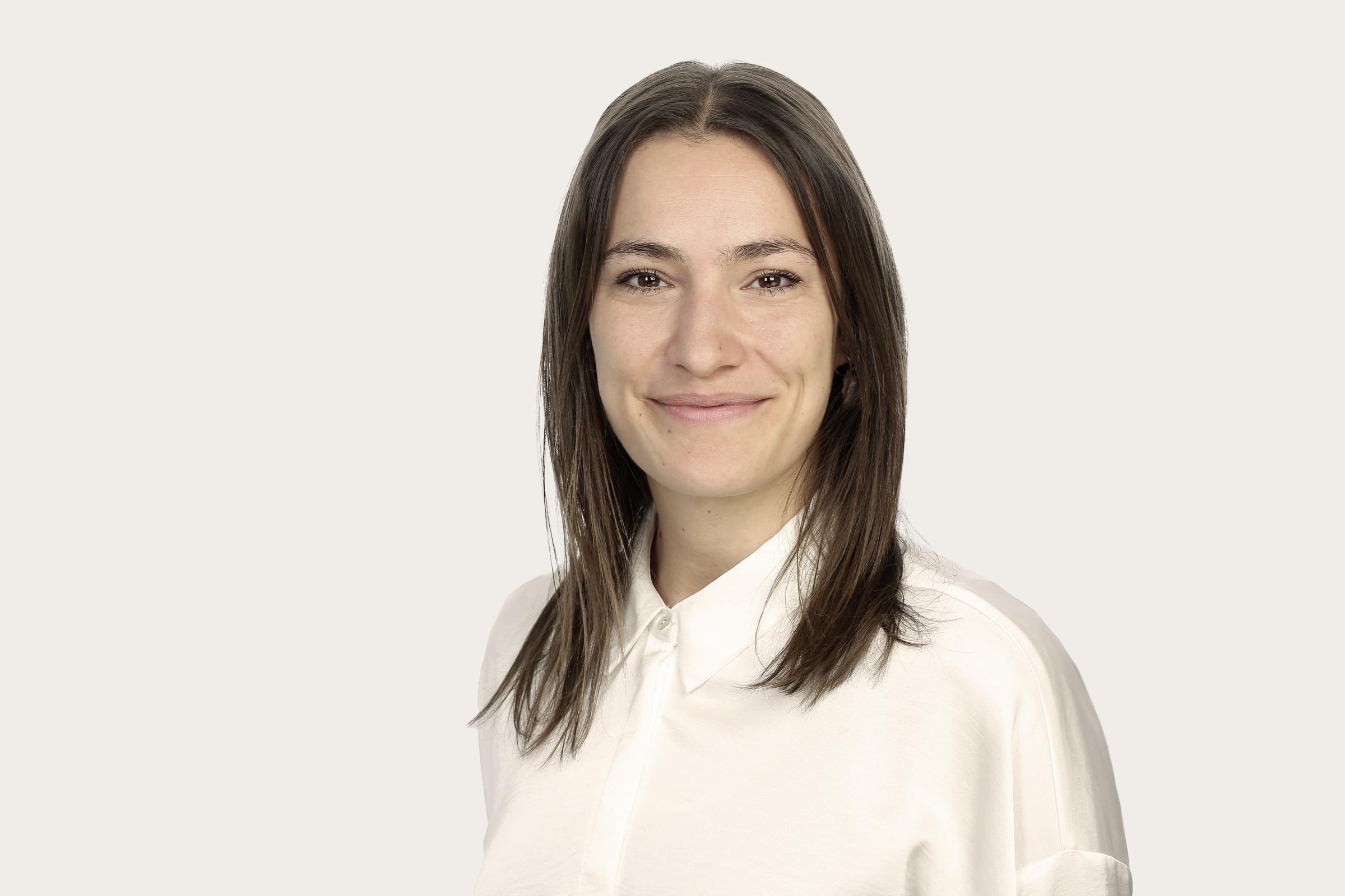 Lisa Lücke, eine Frau mit schulterlangem braunem Haar, trägt ein weißes Hemd.