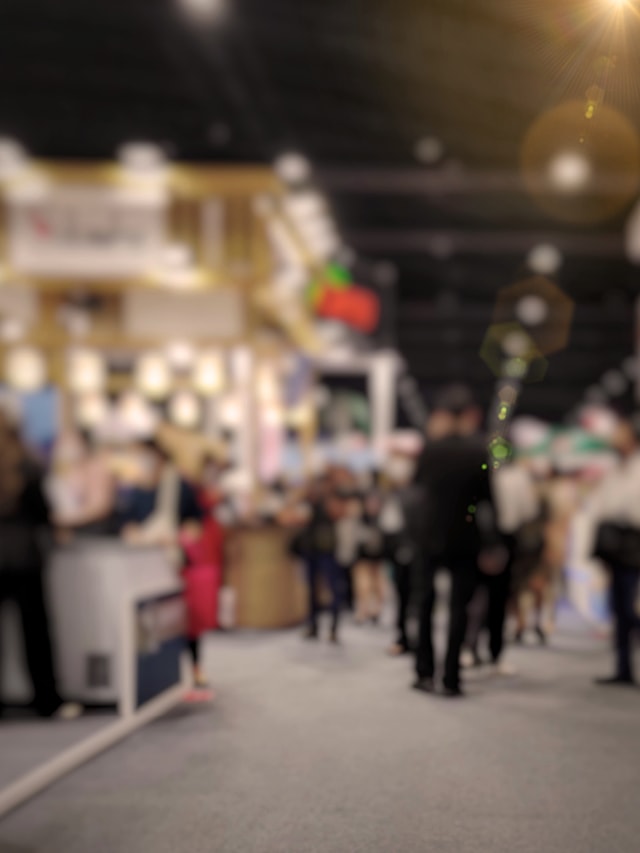 Verschwommene Darstellung eines Gangs auf einer Messe mit mehreren Personen im Hintergrund