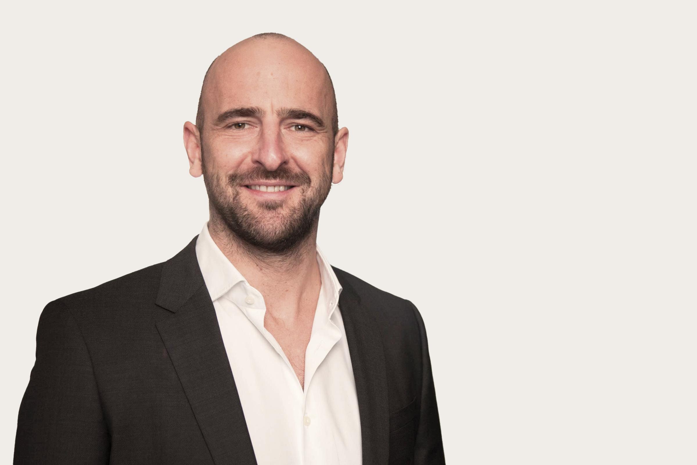 Eine Person trägt ein schwarzes Sakko über einem weißen Hemd.