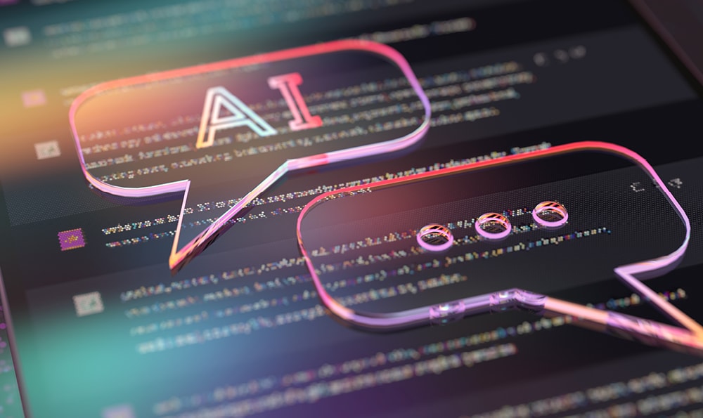 Zwei Sprechblasen auf einem Bildschirm. Die linke enthält "AI" in bunten Farben, die rechte drei Punkte.