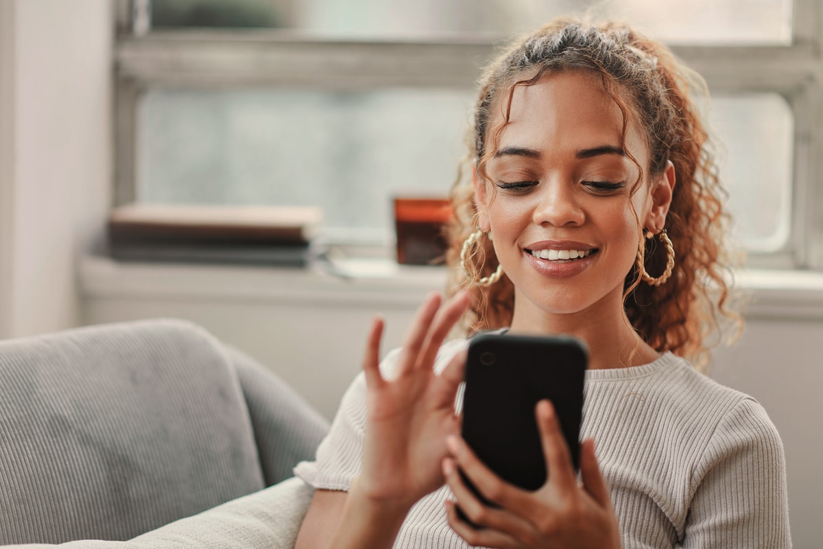 Junge Frau hält Smartphone in der Hand und lächelt