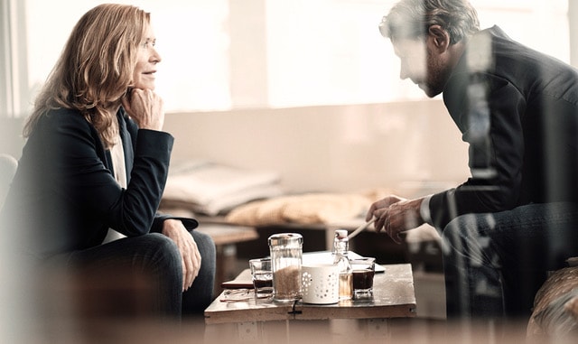 Ein Mann und eine Frau sitzen an einem Sofatisch und unterhalten sich