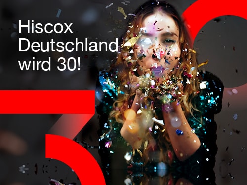 Eine Frau pustet golden glänzende Schnipsel von ihren Händen. Das Bild zeigt außerdem den Schriftzug "Hiscox Deutschland wird 30!" sowie eine große rote 3 und eine 0 jeweils links unten und rechts oben in der Bildecke
