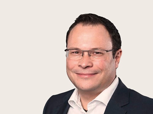 Ronny Schreib trägt ein dunkles Sakko und ein weißes Hemd.