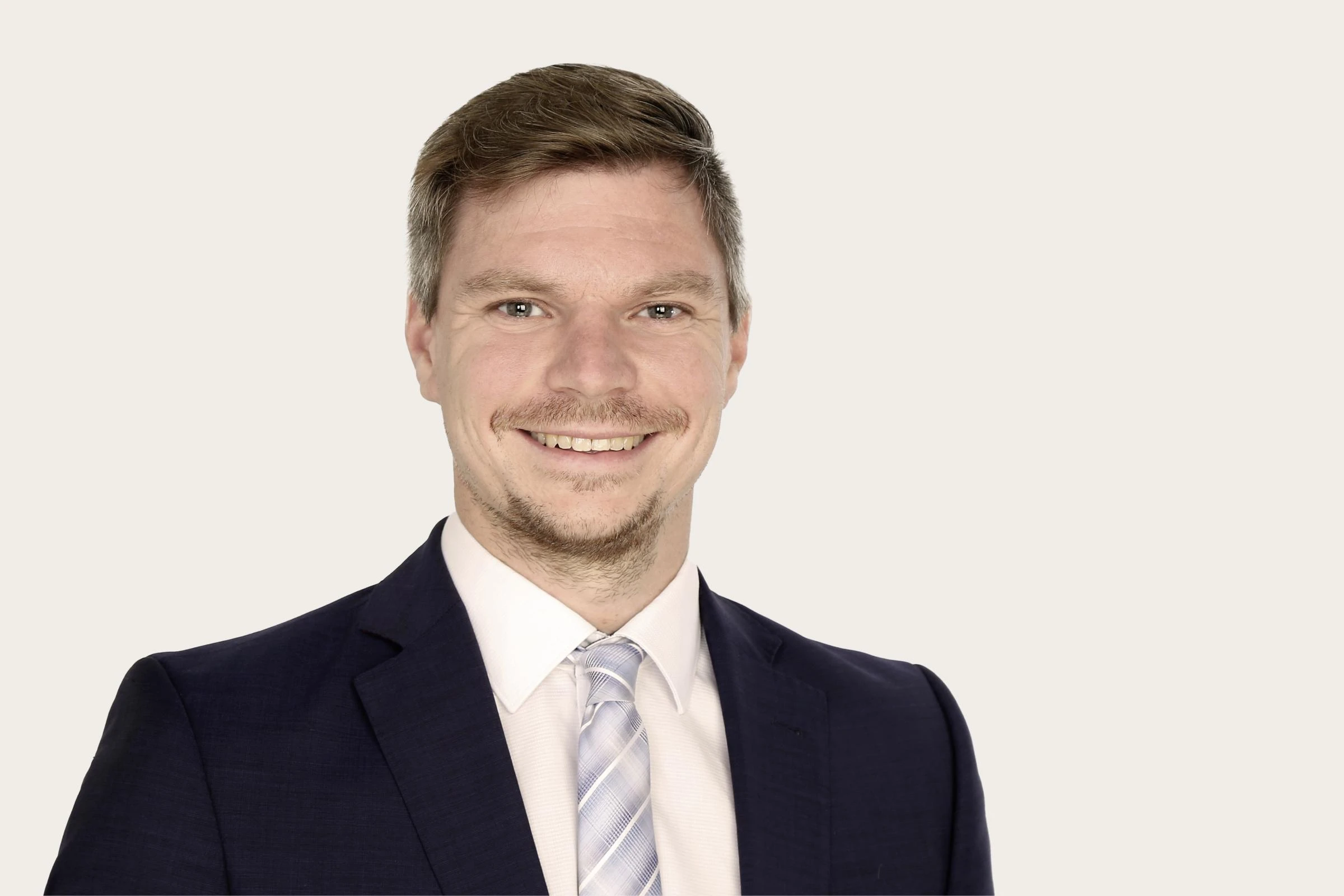 Hiscox Experte Tobias Knoll lächelnd im Anzug und Krawatte.