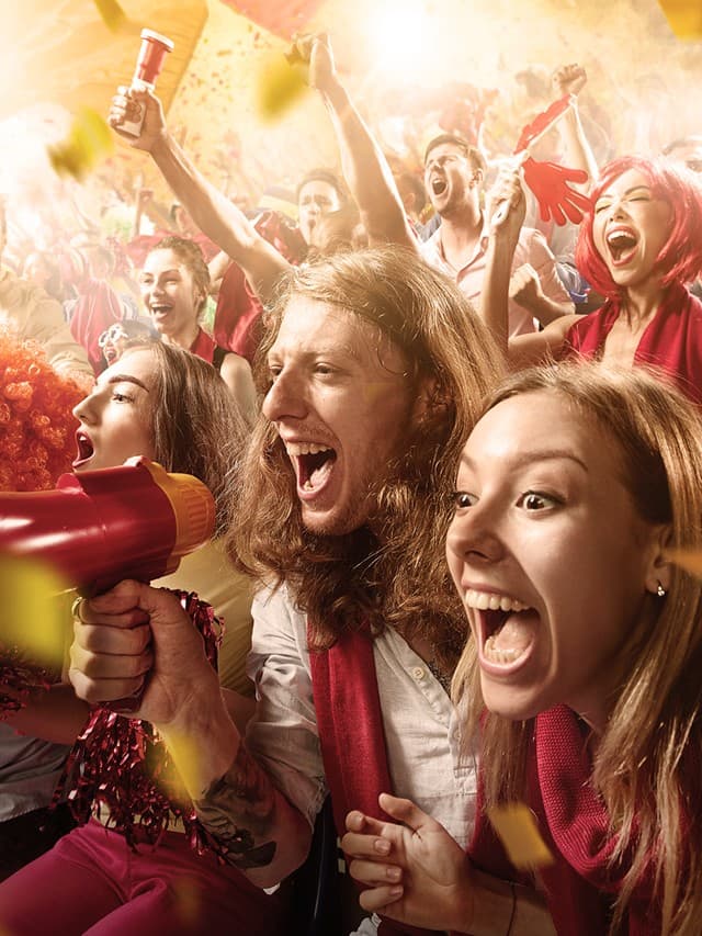 Das Bild zeigt jubelnde Fußballfans im Fußballstadion auf der Tribüne
