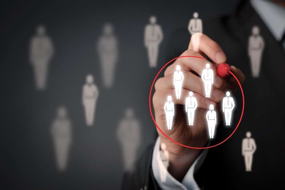 Zielgruppenanalyse: Hand zeichnet roten Kreis um ausgewählte Figuren als Symbol für Zielgruppenfokussierung.