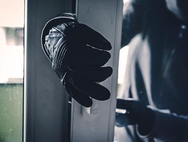 Eine Person mit schwarzen Handschuhen öffnet eine Tür oder ein Fenster.
