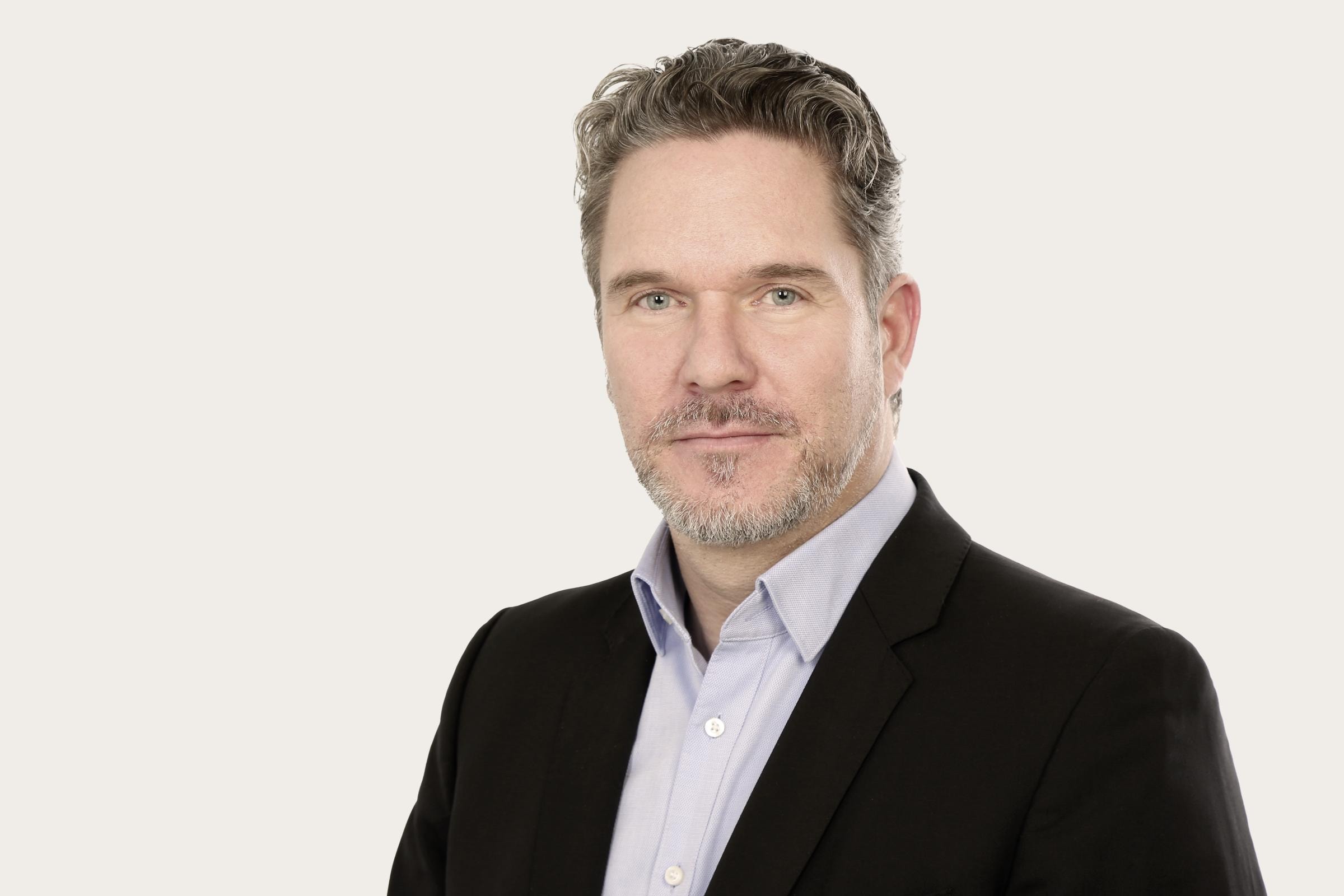 Markus Leenen trägt ein schwarzes Sakko über einem hellblauen Hemd.