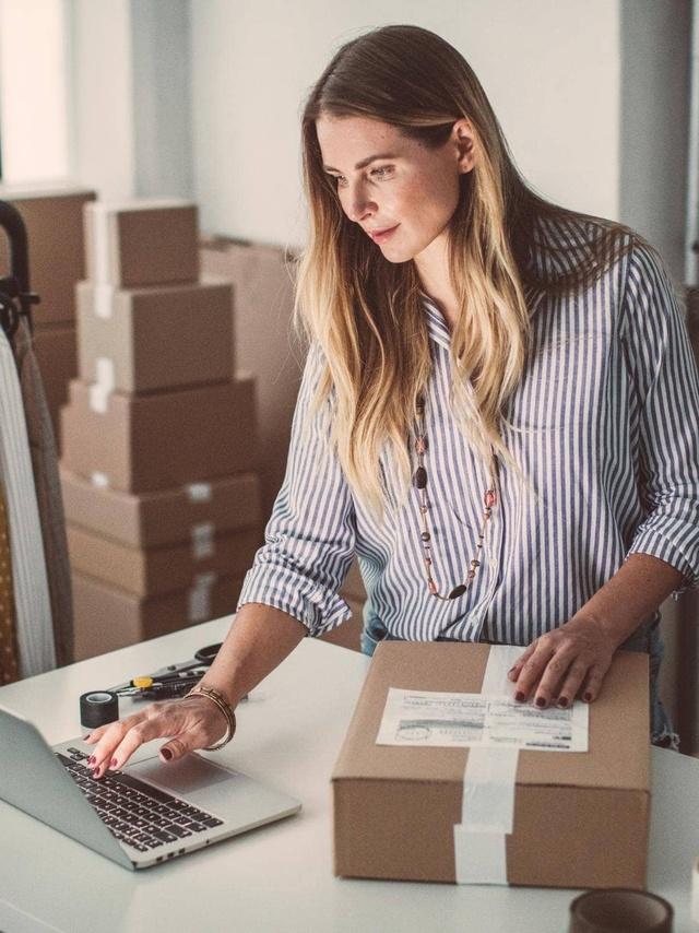 Onlineshop-Versicherung von Hiscox: Onlineshop-Betreiberin arbeitet in ihrem Warenlager am Laptop