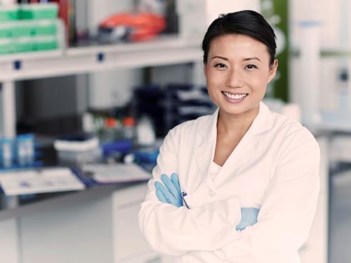 Frau mit Handschuhen steht in einem Labor